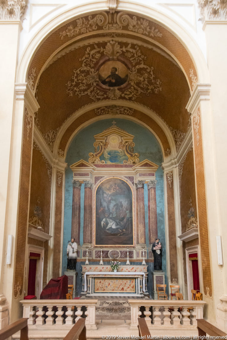 Marble chapel altar with central painting, sculpted figures and richly decorated barrel vault.