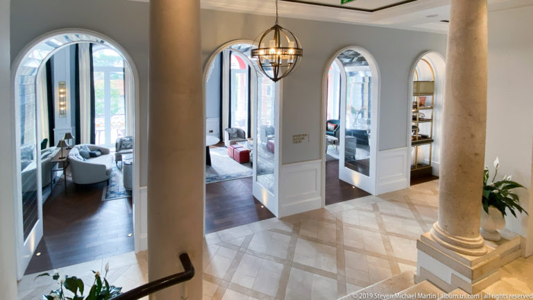Interior with two large stone columns, white arches, polished floor, hanging lantern, and modern lounge seating.