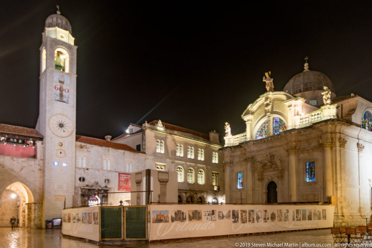 Church of St. Blaise and Dubrovnik City Bell Tower illuminated across Luža Square at night.