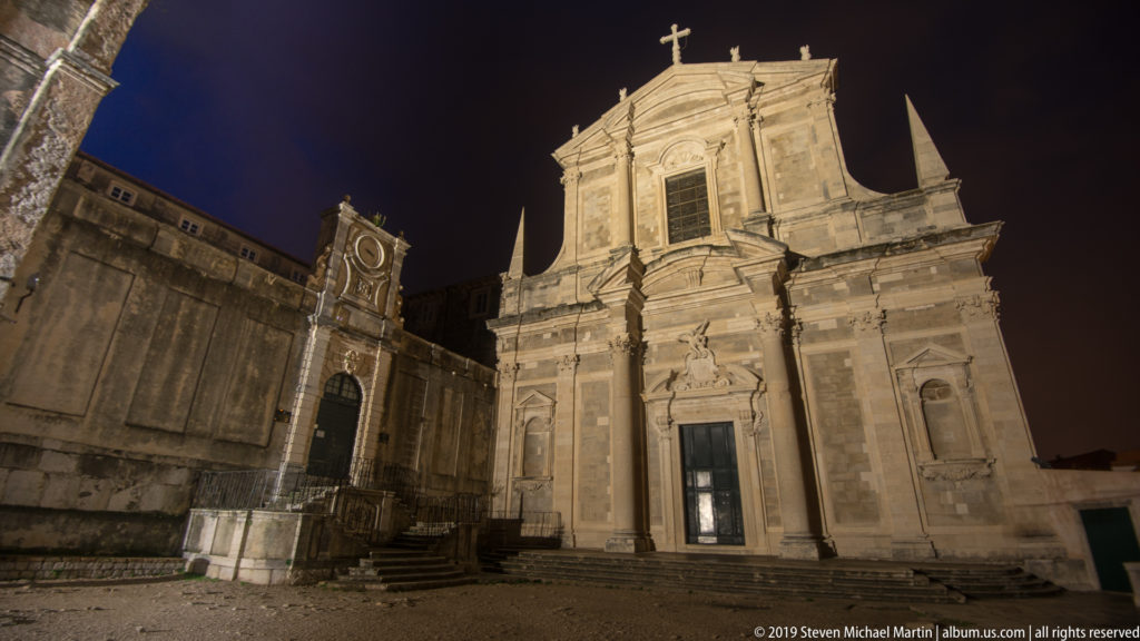 Illuminated Baroque façade of the Church of St. Ignatius of Loyola seen from a low angle at night.