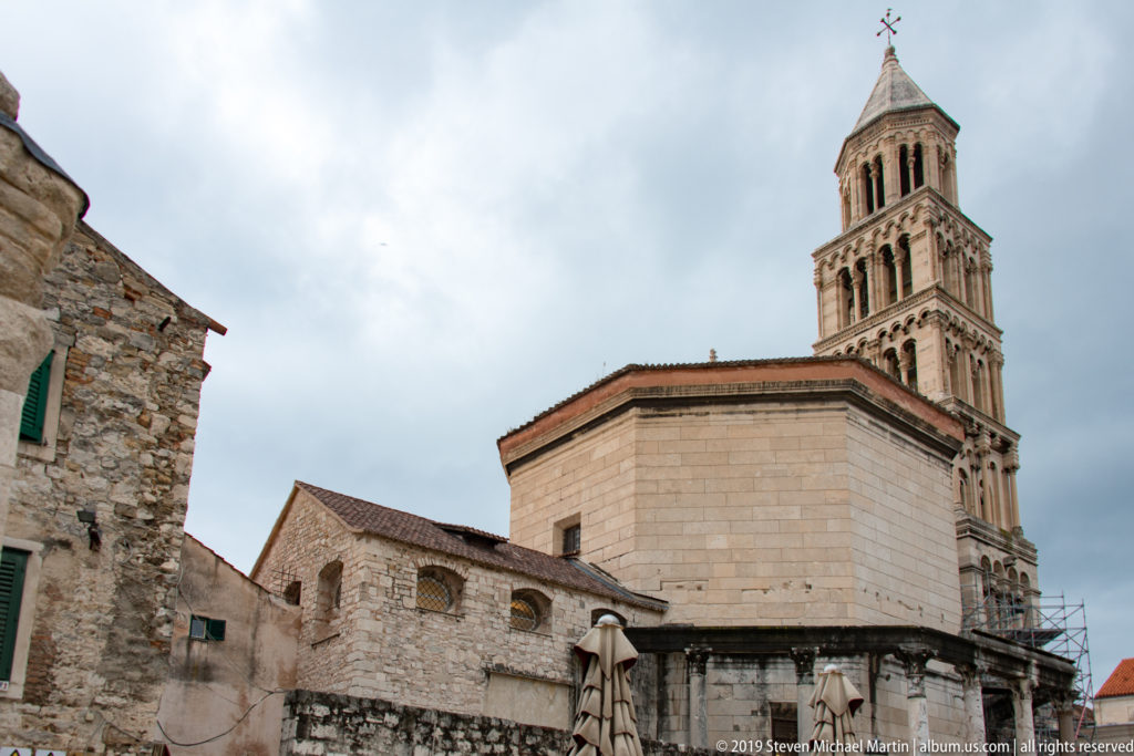 Cathedral of Saint Domnius bell tower rising behind old stone buildings and red-tiled roofs in Split.