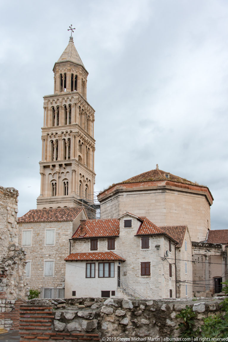 Cathedral of Saint Domnius bell tower and octagonal church rising above tiled roofs, low stone ruins, and pale historic buildings.