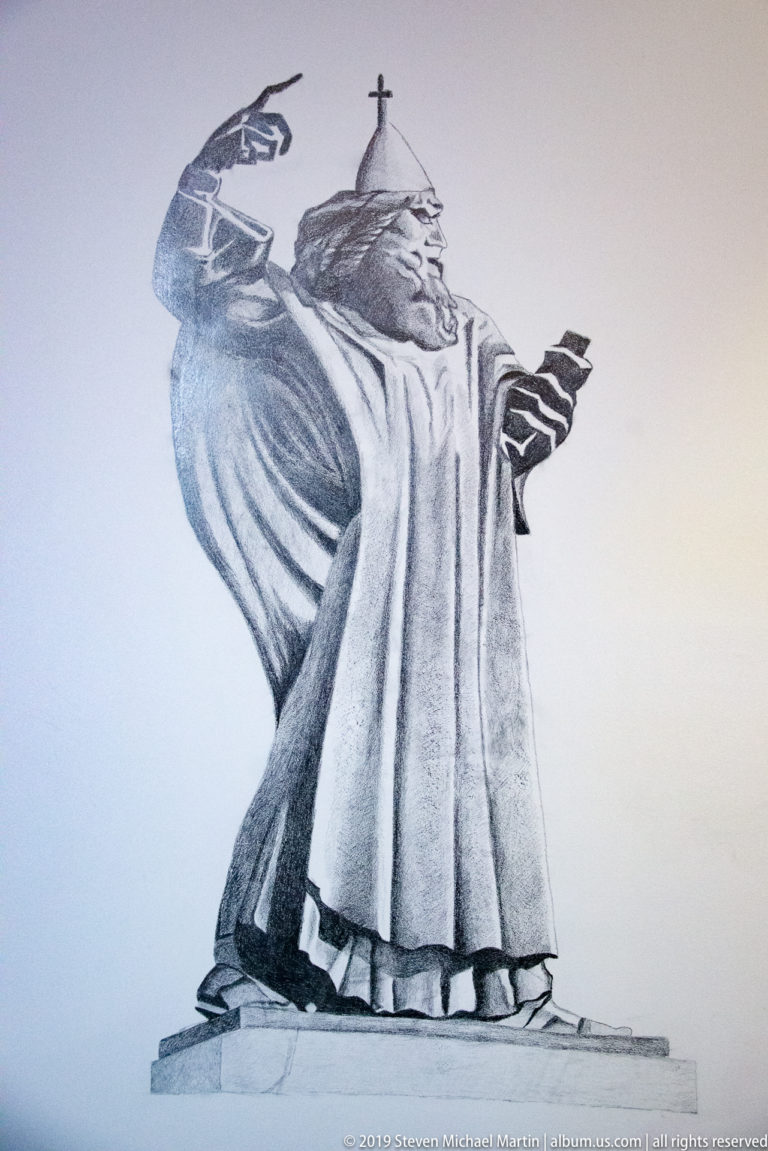 Monochrome drawing of a robed religious figure standing in profile with one arm extended and a staff-like form behind.