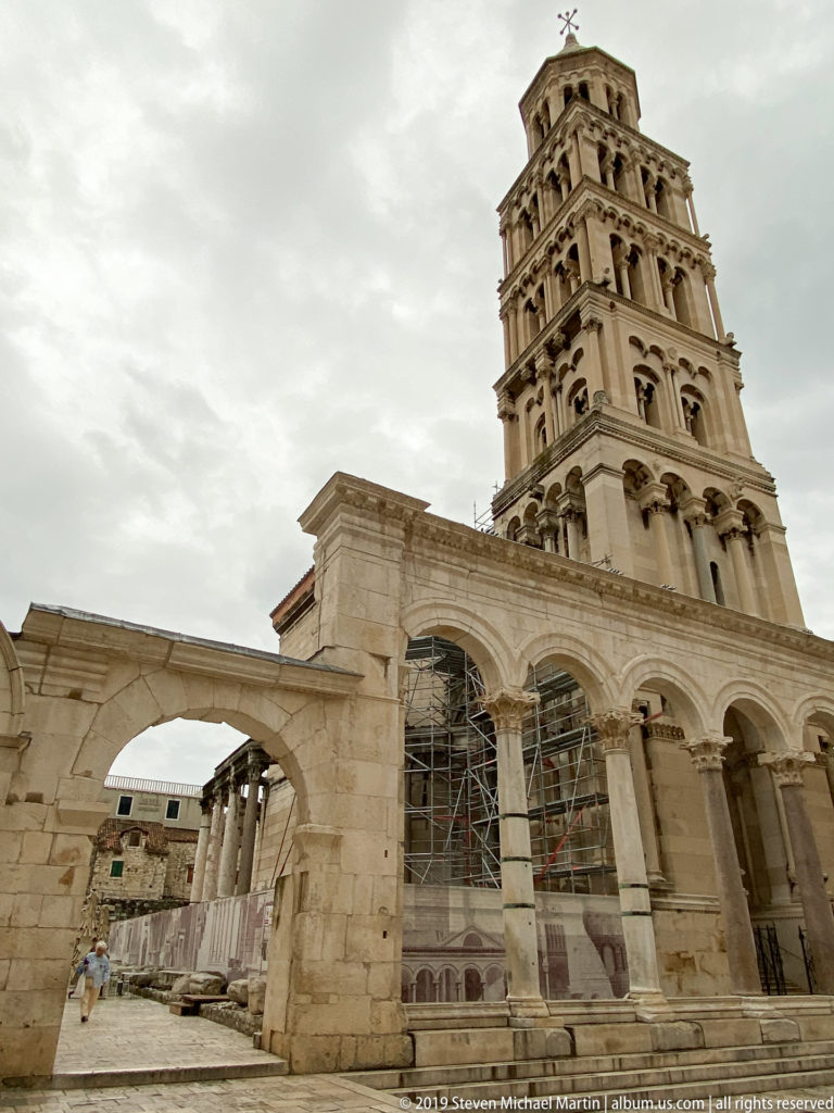 Cathedral of Saint Domnius bell tower above pale stone arcades and palace structures, with scaffolding visible below.