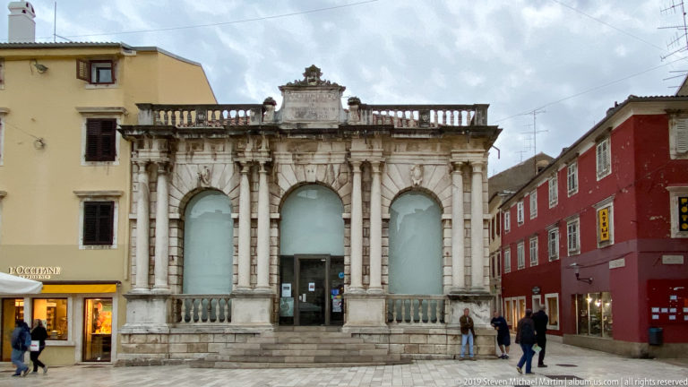 Renaissance City Loggia in Zadar with three tall arched openings, paired columns, stone balustrade, and inscription panel.