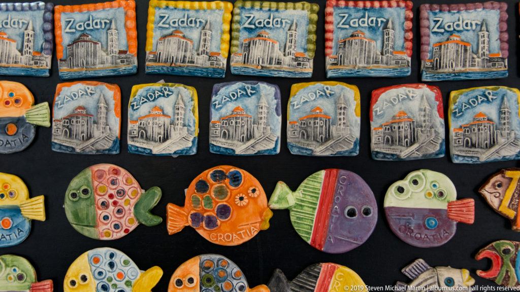 Colorful ceramic souvenir magnets shaped as fish and plaques, many labeled Zadar or Croatia.