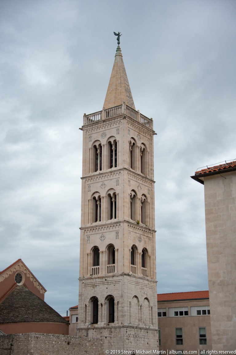 Full view of St. Anastasia Cathedral bell tower with stacked open arcades and steep pyramidal roof.