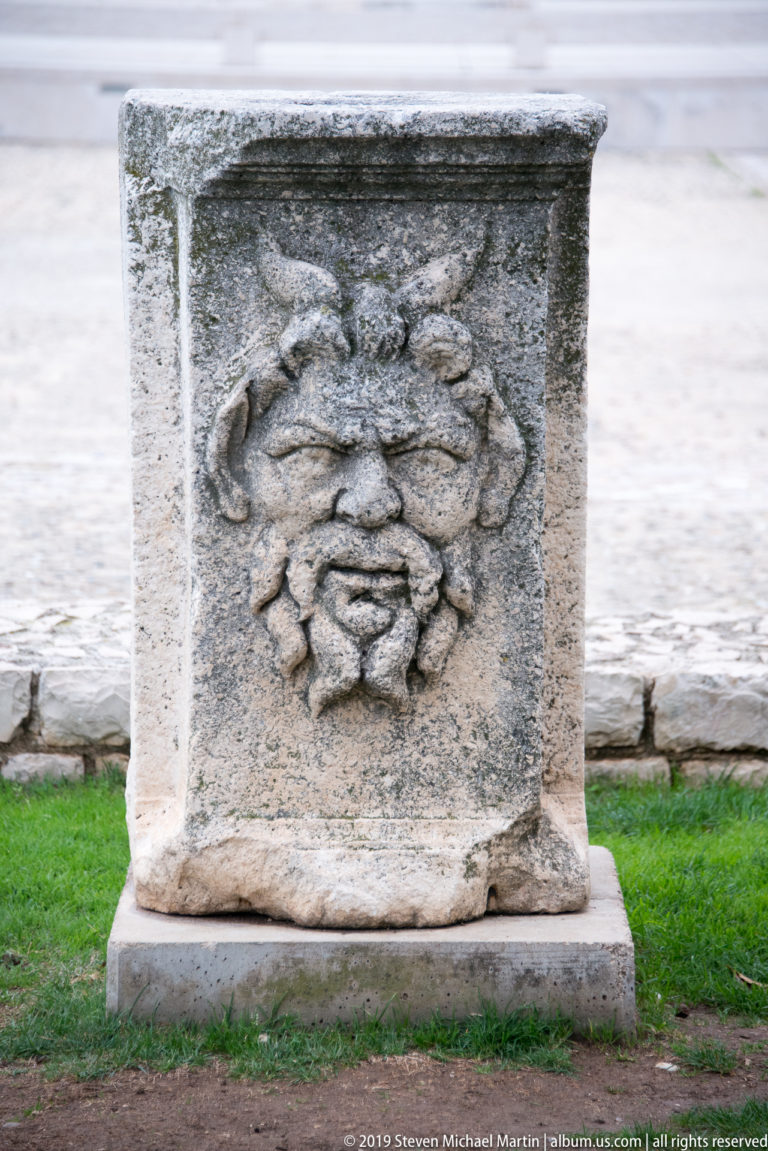 Rectangular ancient stone block carved with a large layered rosette in relief.