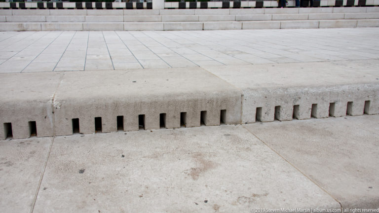 Long limestone riser of Zadar’s Sea Organ punctuated by evenly spaced narrow rectangular openings.