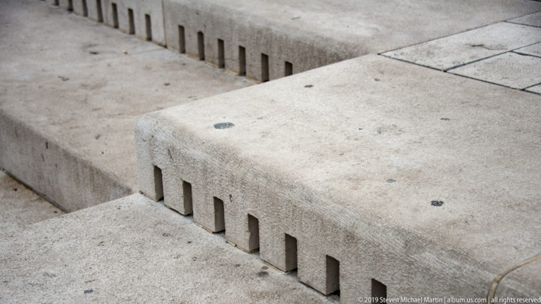 Close view of pale stone Sea Organ steps with a row of narrow rectangular sound openings along the riser.