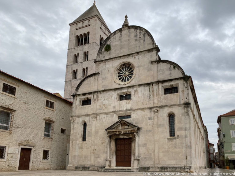 Close frontal view of St. Mary’s Church with curved gables, central rose window, narrow windows, and bell tower.