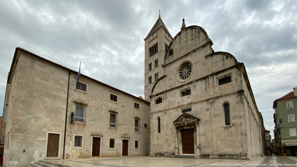Stone façade of St. Mary’s Church in Zadar with curved gables, rose window, classical portal, and bell tower.