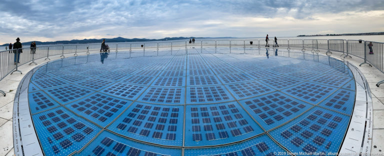 Large circular field of blue solar panels at Zadar’s Greeting to the Sun installation beside the Adriatic waterfront.