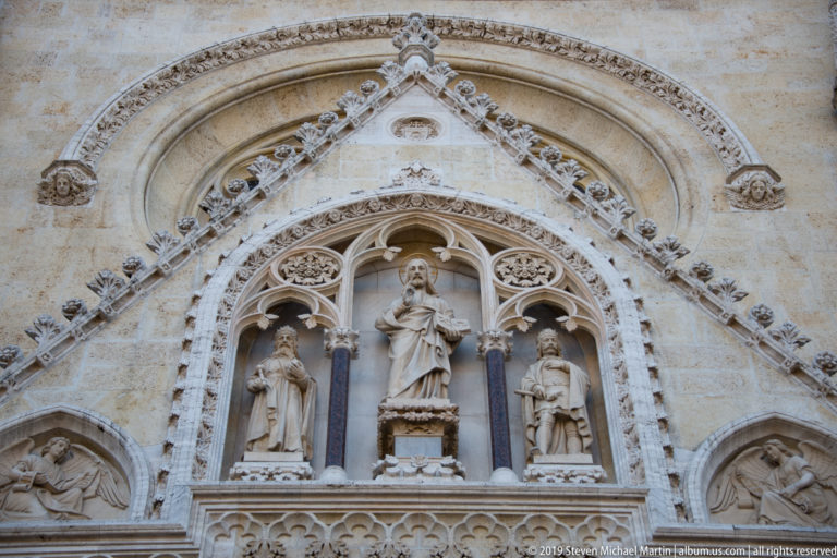 Gothic Revival portal sculpture at Zagreb Cathedral with standing saints, pointed arches, reliefs, tracery, and carved foliage.