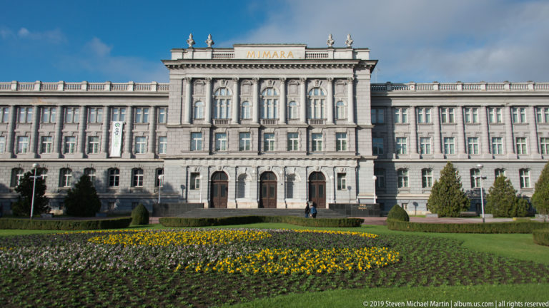 Full façade of Zagreb’s Mimara Museum behind lawns and flower beds, with MIMARA visible above the central pavilion.