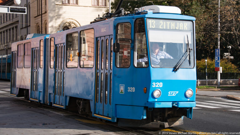 Blue ZET route 13 tram marked Žitnjak approaches on tracks along a Zagreb street.