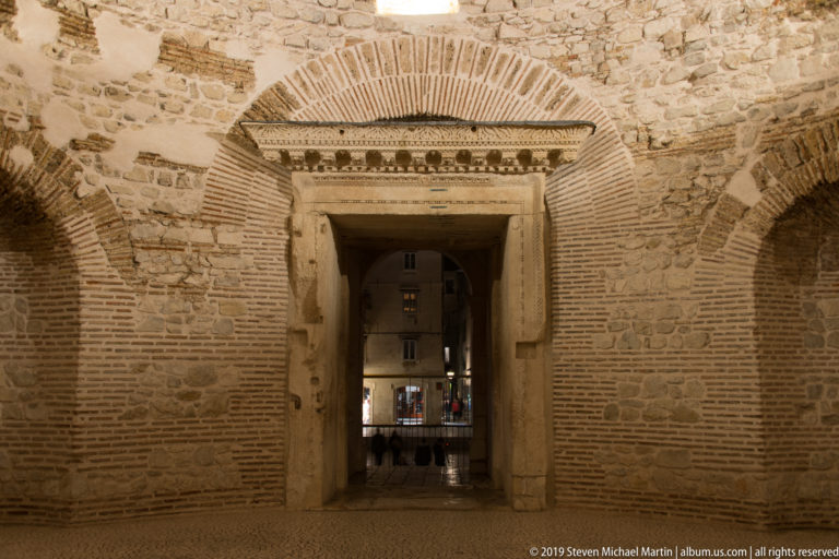 Large rectangular stone doorway beneath a brick arch in the vaulted substructures of Diocletian’s Palace, with another room visible beyond.