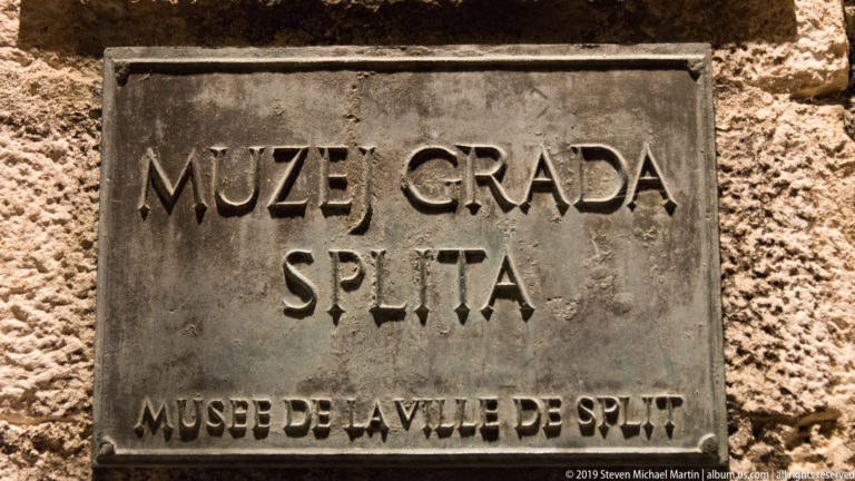 Metal plaque on rough stone reading “MUZEJ GRADA SPLITA” with the French translation “MUSÉE DE LA VILLE DE SPLIT.”