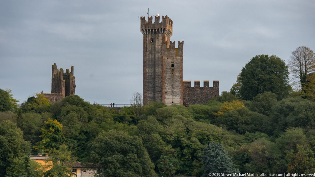 Crenellated medieval castle towers rising above dense trees on a hill at Valeggio sul Mincio.