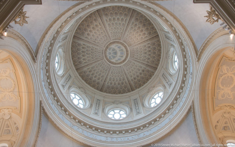 Coffered pale dome with radial ribs, central roundel, and oval windows inside the Church of Sant'Uberto.