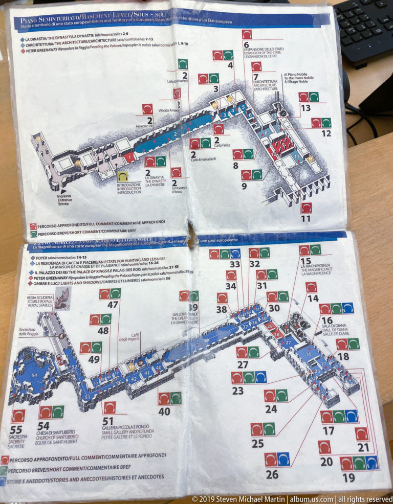 Folded visitor map on a table showing numbered plans, colored routes, and labels for the La Venaria Reale complex.
