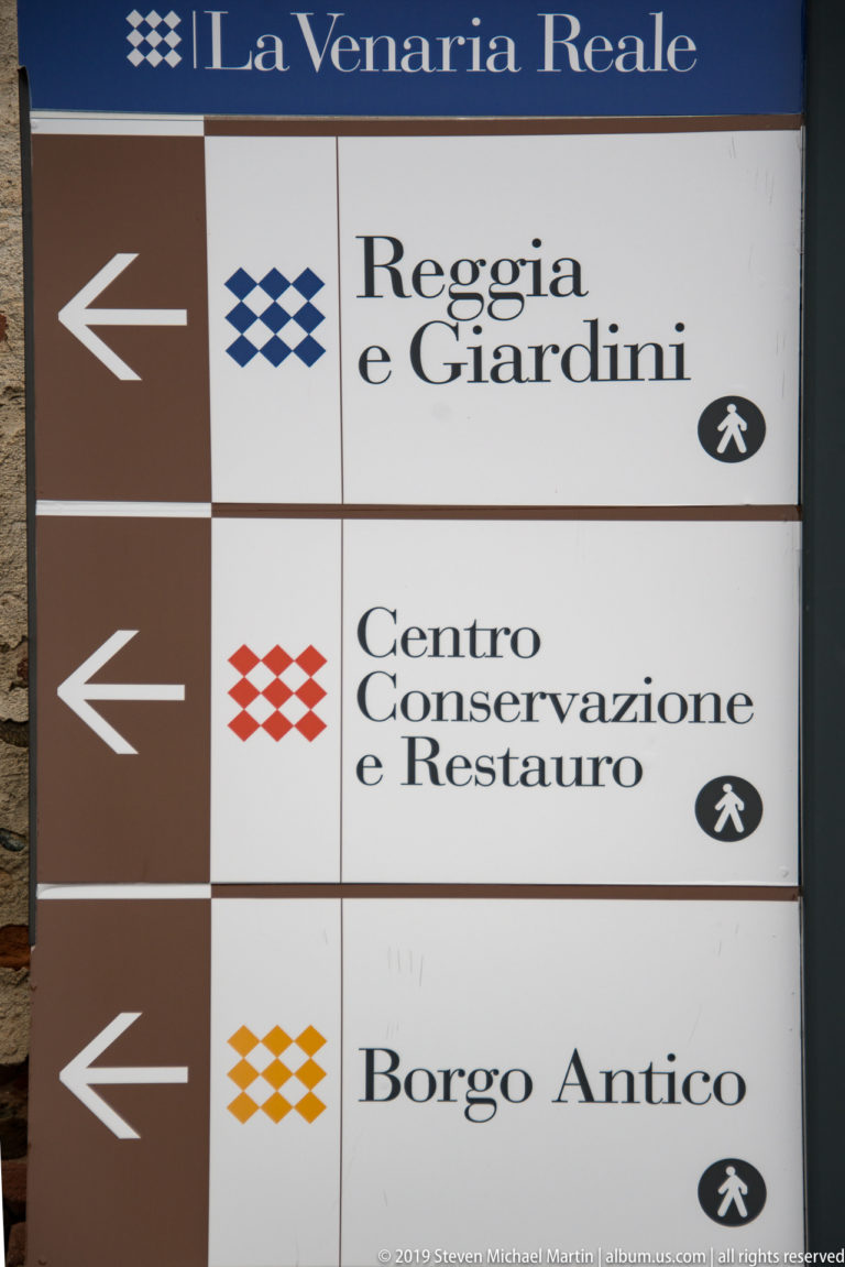 Directional sign pointing left to Reggia e Giardini, Centro Conservazione e Restauro, and Borgo Antico.