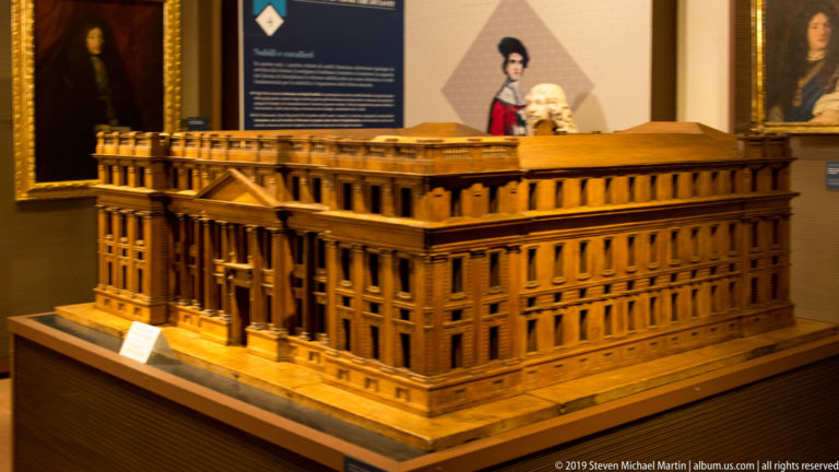 Oblique view of a wooden palace model showing its long side elevation, repeated bays, and roof balustrade.