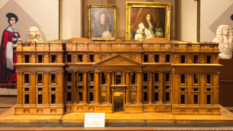 Wooden model of a symmetrical palace façade with central columned portico, triangular pediment, and long wings.