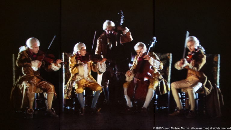 Five period-costumed string musicians performing in Peter Greenaway’s Ripopolare la Reggia multimedia installation.