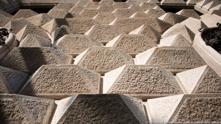 Close-up of repeated pyramid-shaped stone blocks forming a deeply textured diamond-point rusticated surface.