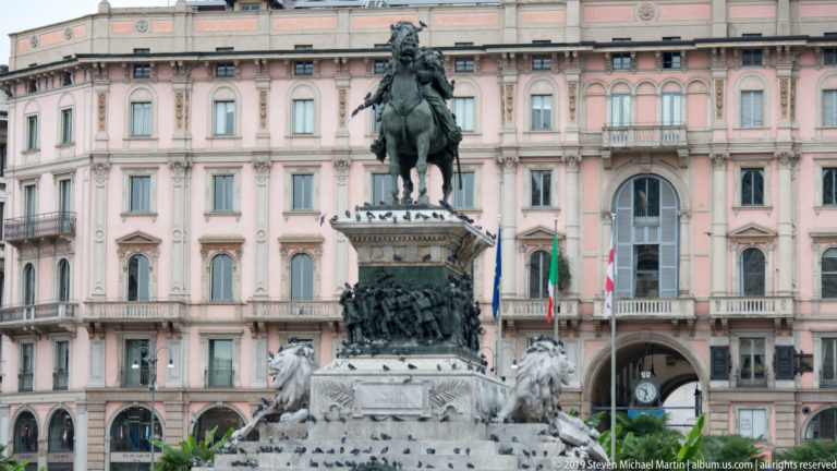 Equestrian monument to Victor Emmanuel II with bronze reliefs and stone lions in Milan’s Piazza del Duomo.