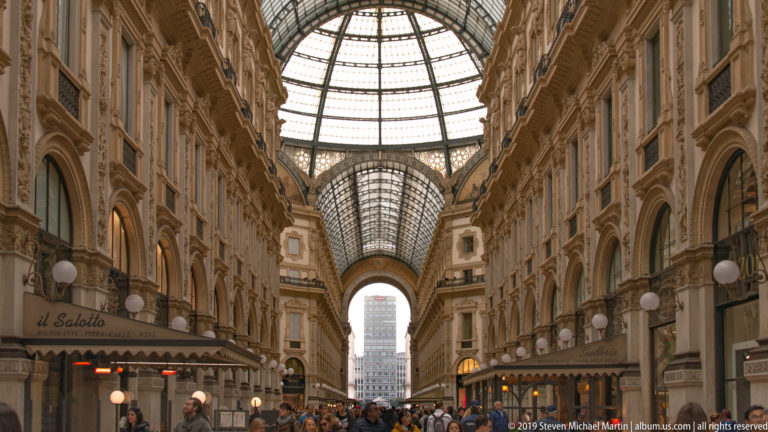 Long interior view through the Galleria Vittorio Emanuele II beneath its barrel-vaulted glass roof.