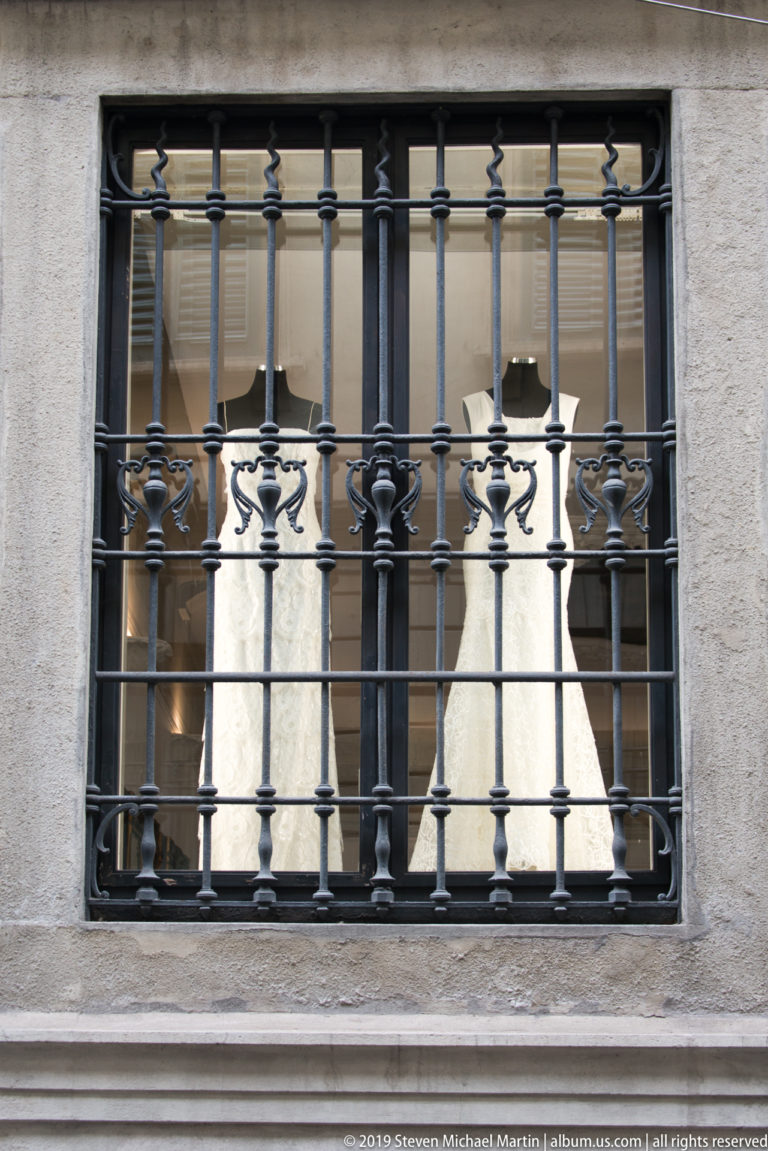 Rectangular window with ornate black wrought-iron bars set into a pale stone wall.