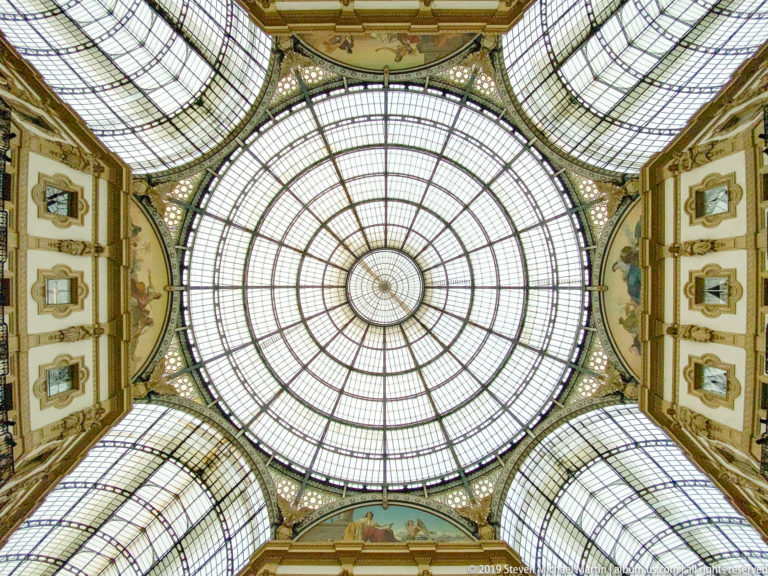 Upward view of the glass-and-iron central dome inside Milan’s Galleria Vittorio Emanuele II.
