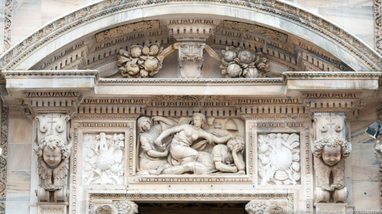 Marble façade relief with a reclining central figure, attendants, masks, garlands, pilasters, and a shallow pediment.