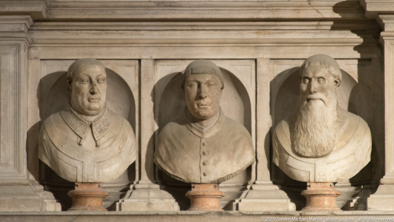 Three marble portrait busts of male clerical or civic figures set side by side in shallow arched niches.