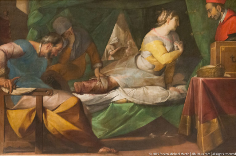 Religious painting with attendants gathered around a reclining figure on a bed, rendered in green, red, blue, and yellow.