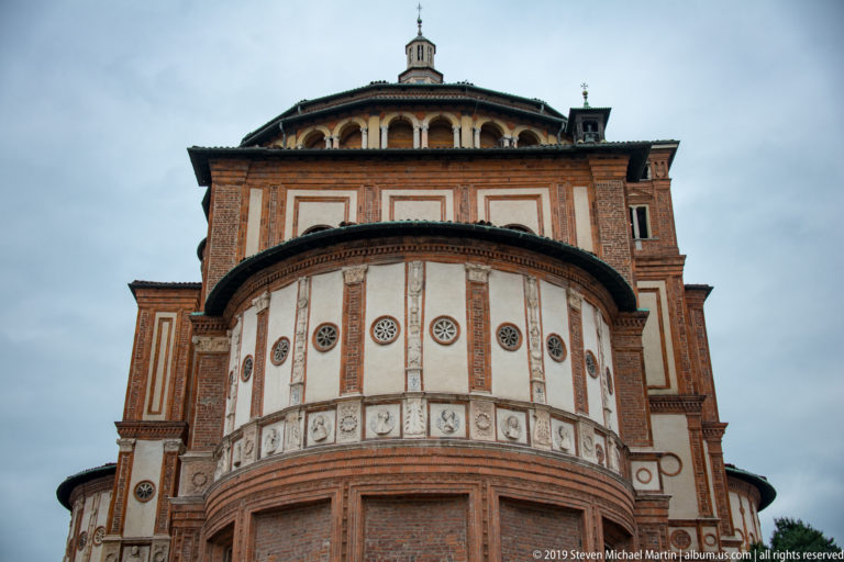 Upward view of the Santa Maria delle Grazie tribune, with a rounded decorated drum beneath a taller brick-and-plaster upper structure.