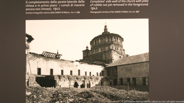 Black-and-white postwar view of the rebuilt south wall of Santa Maria delle Grazie with the tribune rising behind construction debris.