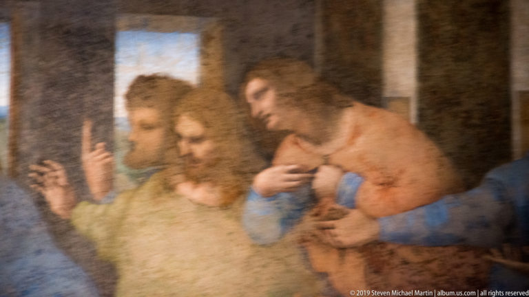 Close detail of Thomas raising one finger behind James the Greater and Philip touching his chest in The Last Supper.