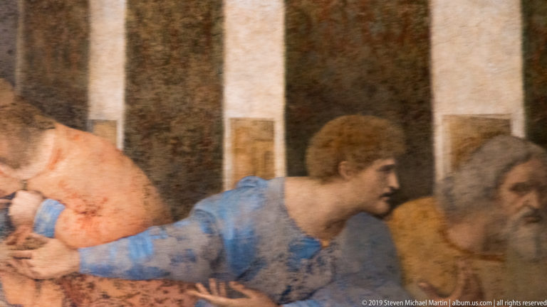 Matthew in blue leans and gestures toward Jude Thaddeus and Simon at the right edge of The Last Supper.