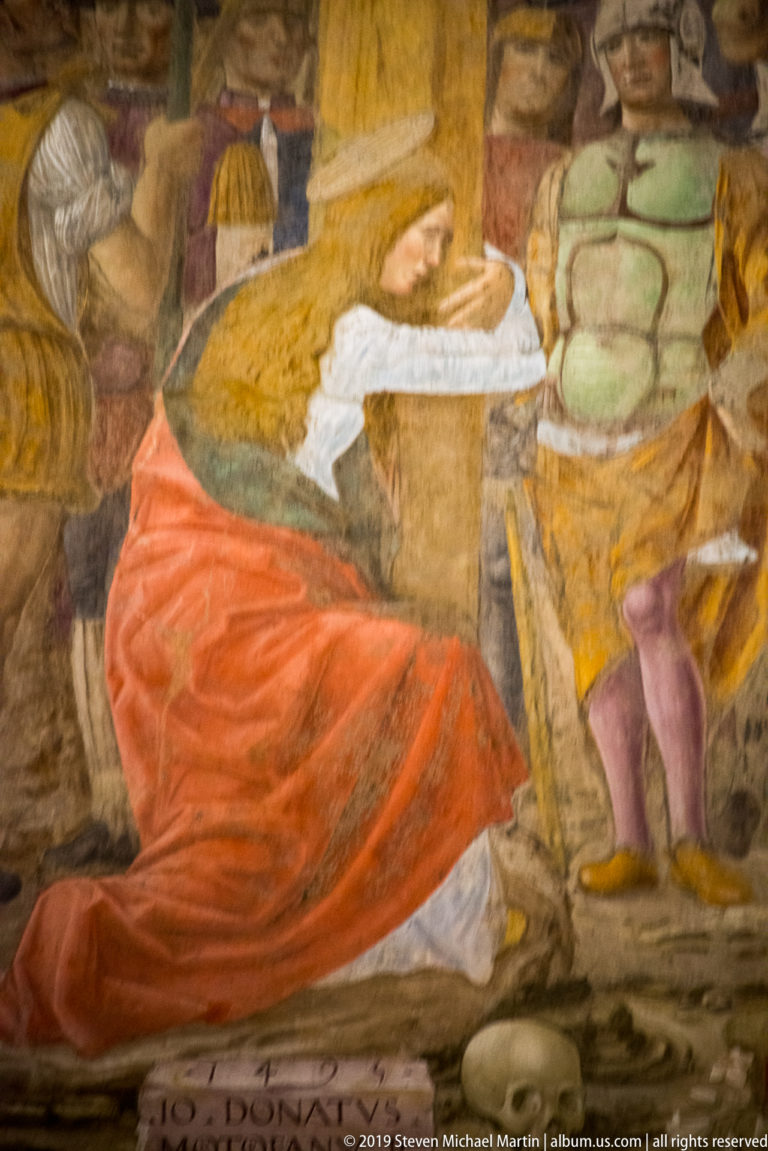Kneeling male figure in a sweeping red mantle beside standing attendants in a worn detail of Montorfano’s Crucifixion.