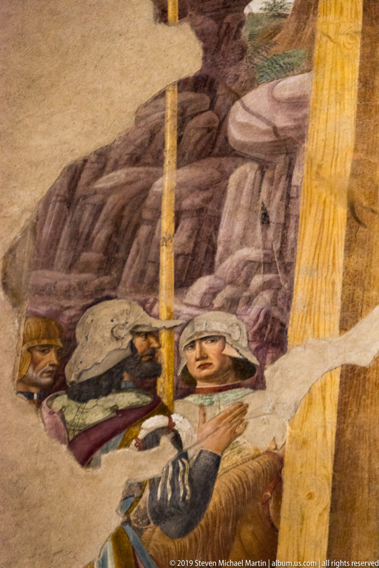 Helmeted soldiers behind a pale diagonal cross beam in a heavily damaged detail of Montorfano’s Crucifixion.