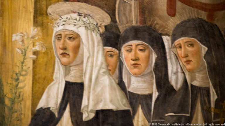 Four women in black-and-white Dominican habits, including a foreground figure with a white veil and floral crown.