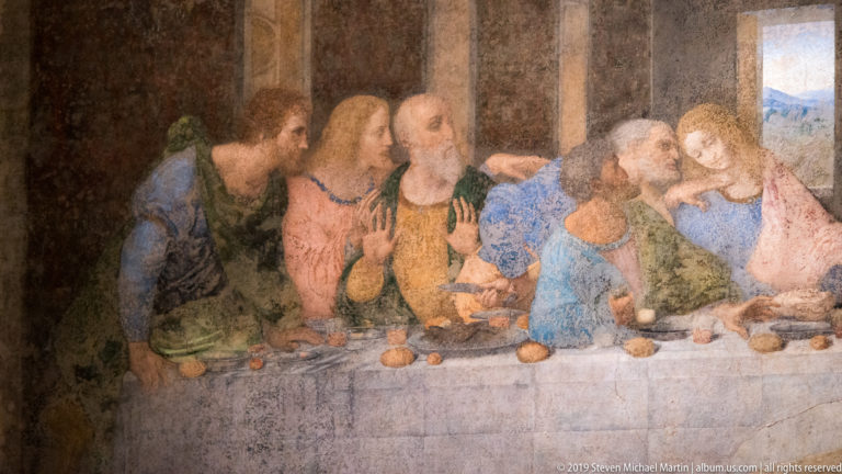 Close view of apostles at the right end of The Last Supper, including a bearded man raising both hands.
