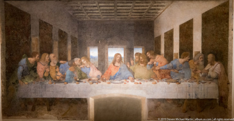 Centered full view of The Last Supper, with Christ beneath the middle window and apostles arranged along the table.