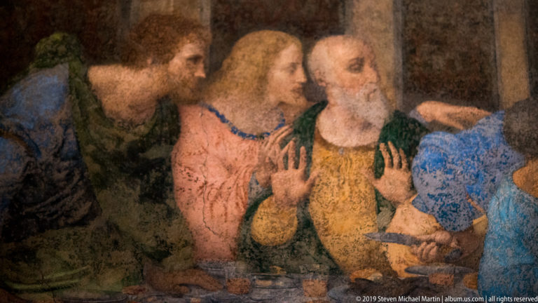 Three apostles at the right end of The Last Supper, including a bearded figure raising both hands.