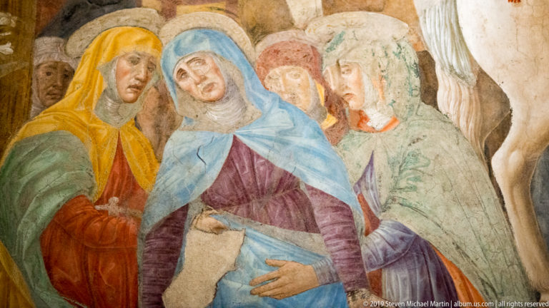 Group of mourning women in blue, purple, yellow, and green garments beneath Montorfano’s Crucifixion.