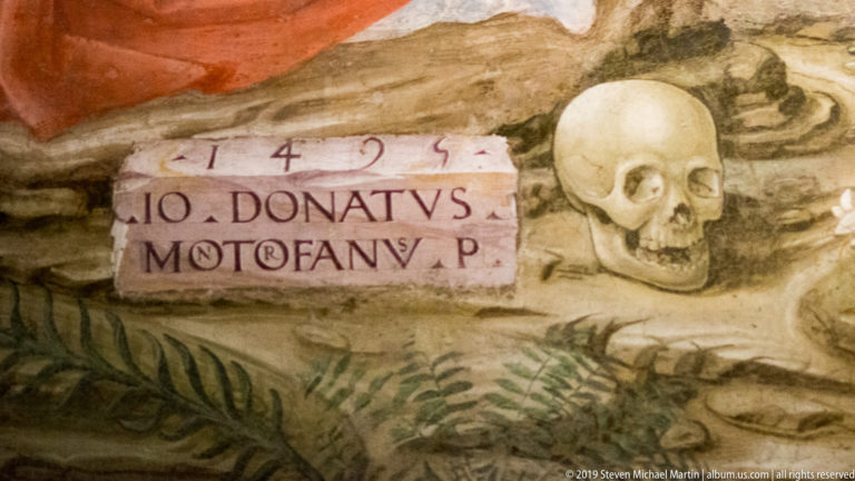 Skull beside the painted signature of Donato Montorfano in a worn detail of the Crucifixion fresco.