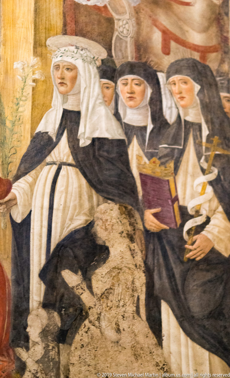 Detail of Montorfano’s Crucifixion showing Dominican women in black-and-white habits, one holding a red book, on worn painted plaster.